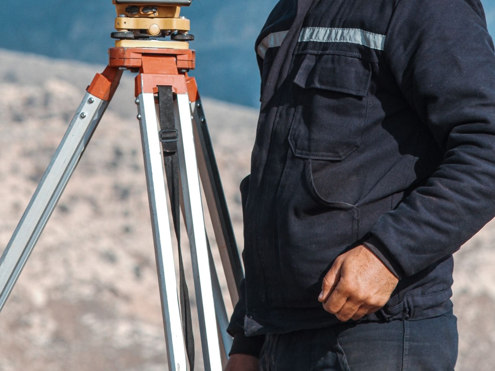 Land surveyor with theodolite on a mountain plot for site review